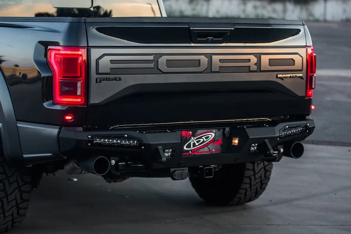 2017 Ford Raptor Honeybadger Rear Bumper With Tow Hooks And Backup Sensors With 10 sr LED Light Bar Mounts And Dually Mounts in Hammer Black With Satin Black Panels.